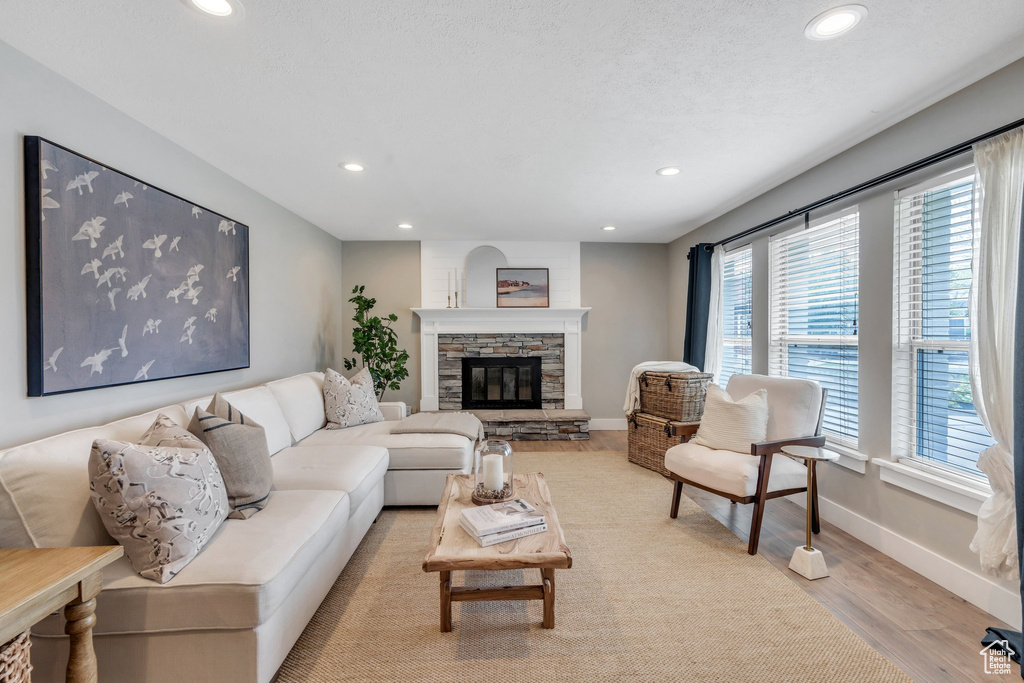 Living room featuring recessed lighting, wood finished floors, baseboards, and a stone fireplace