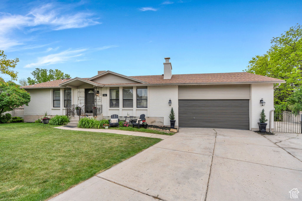 Ranch-style house featuring a garage, concrete driveway, a chimney, and brick siding
