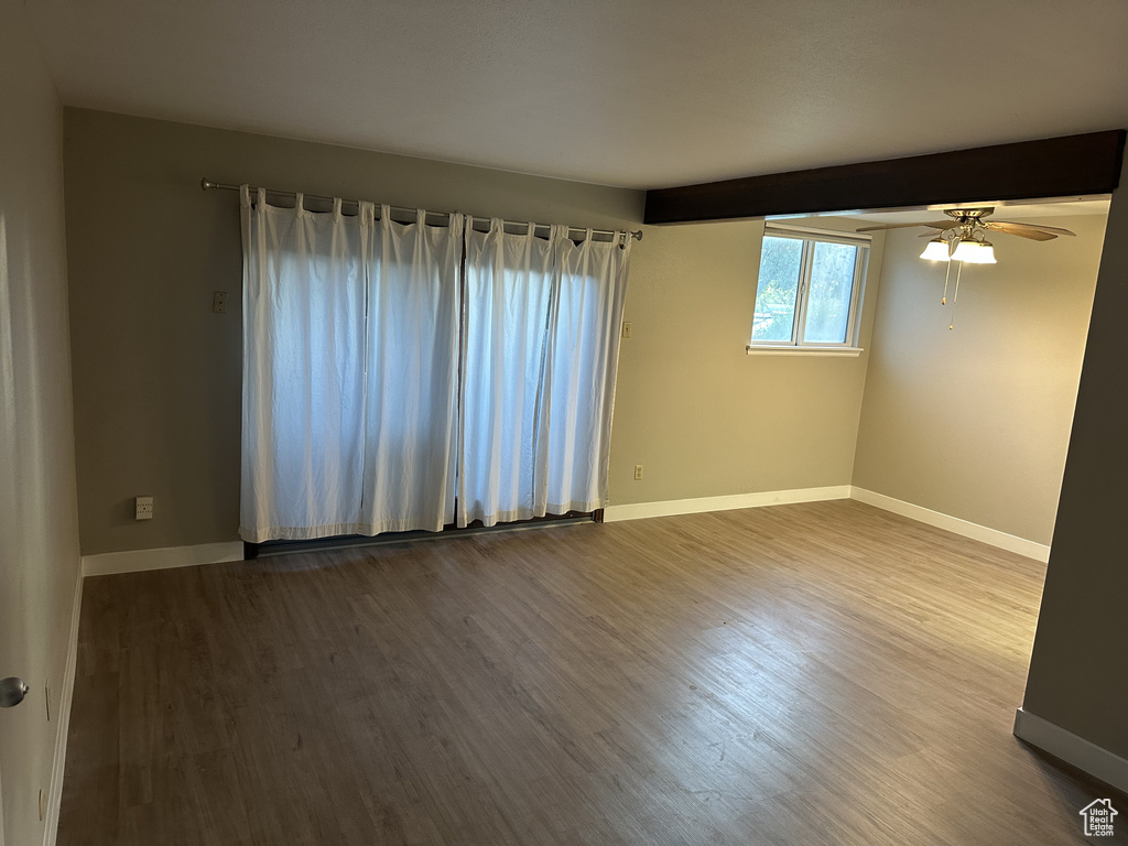 Spare room with dark wood-style floors, a ceiling fan, and beam ceiling