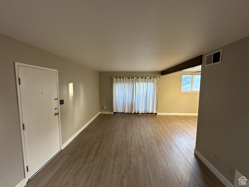 Unfurnished living room with dark wood-type flooring and baseboards