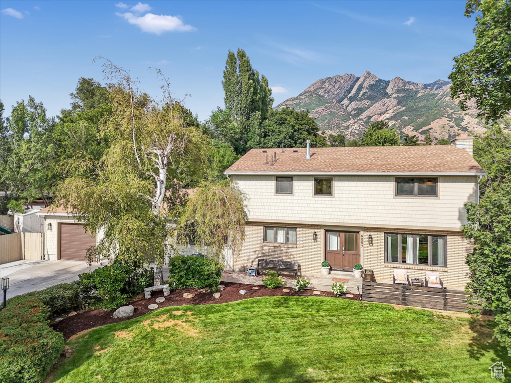 Front facade featuring a mountain view, a front yard, and a garage