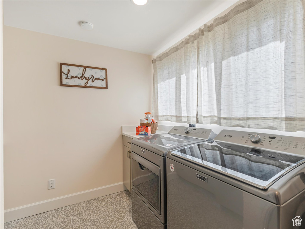 Washroom featuring cabinets and washing machine and clothes dryer