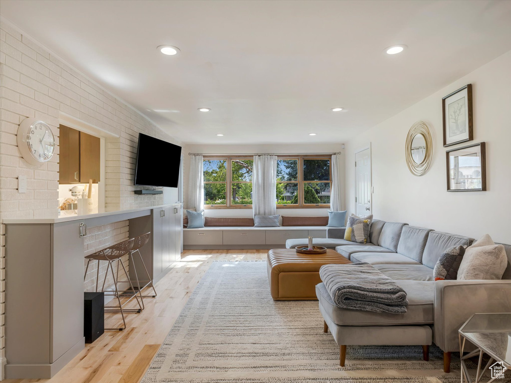 Living room with a fireplace, light hardwood / wood-style flooring, and brick wall