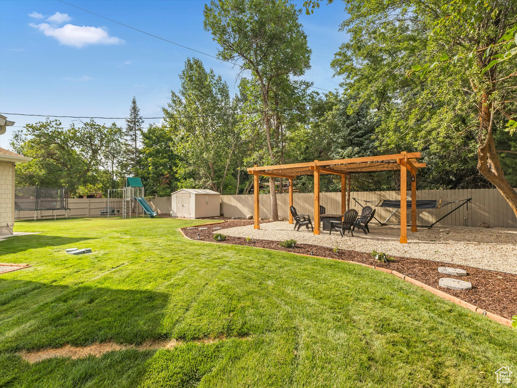 View of yard featuring a pergola, a playground, and a storage shed