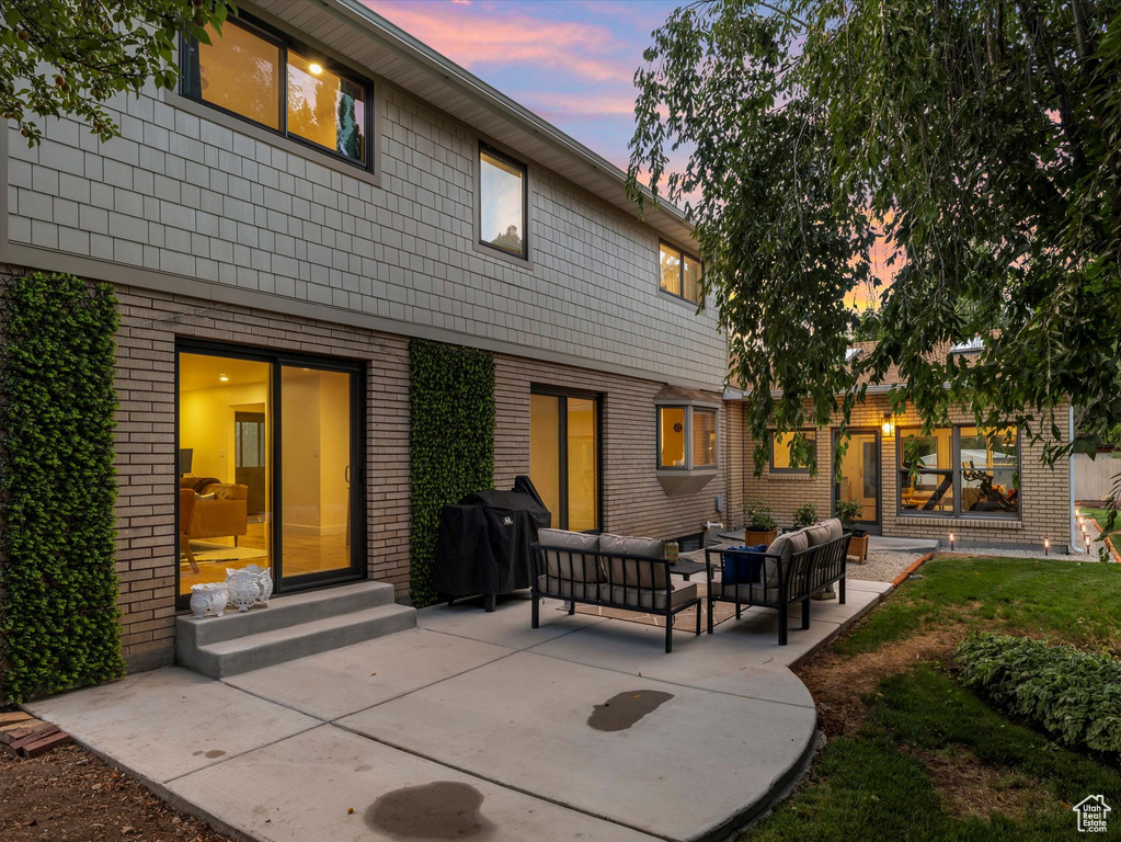 Back house at dusk with outdoor lounge area and a patio