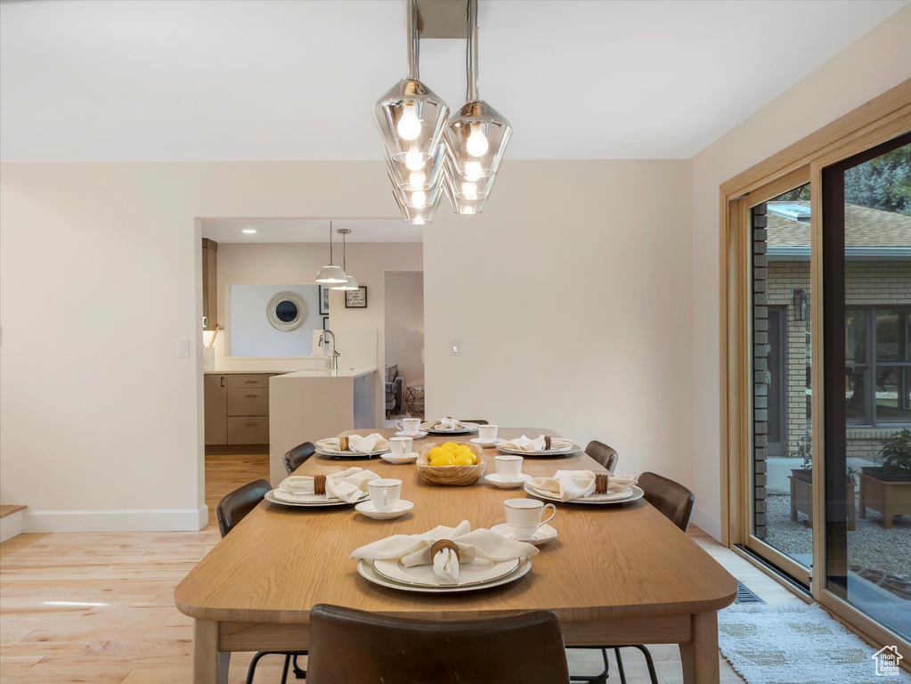 Dining space with light wood-type flooring and an inviting chandelier