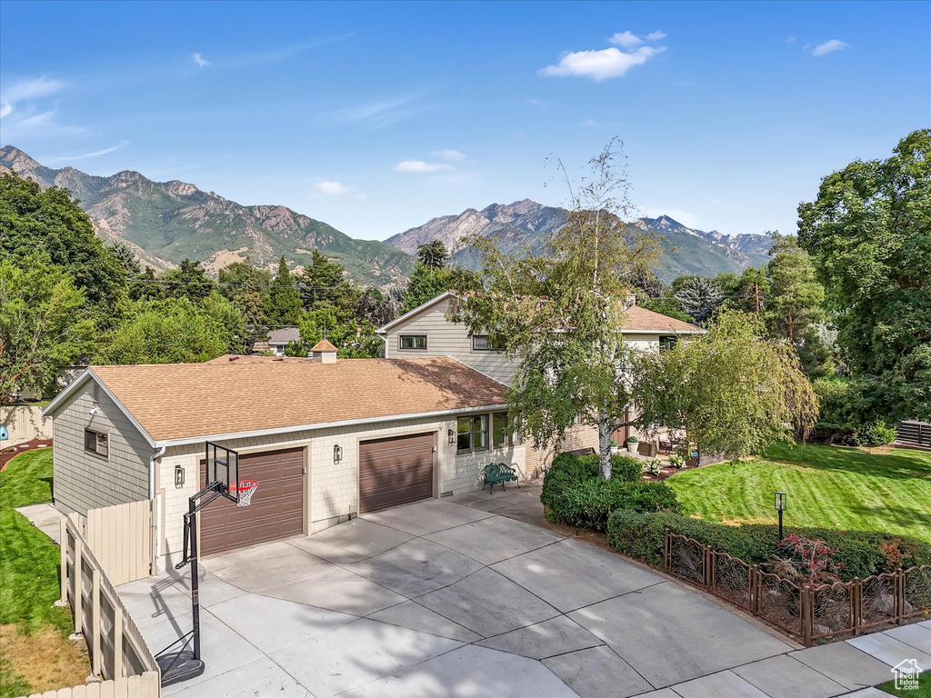 View of front of property with a mountain view, a front lawn, and a garage