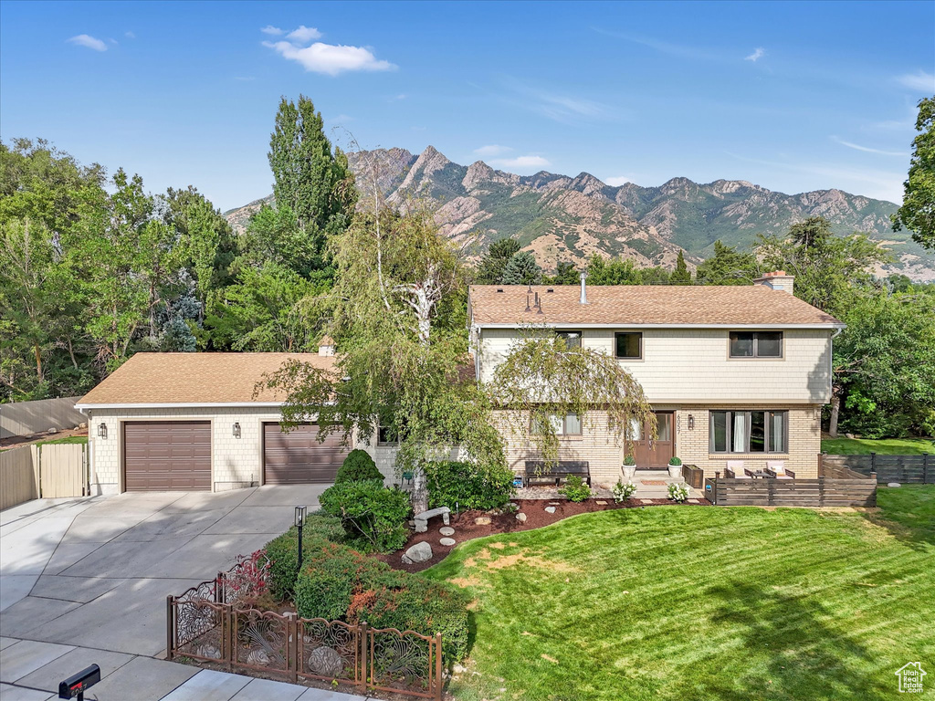 View of front of property with a mountain view, a front yard, and a garage