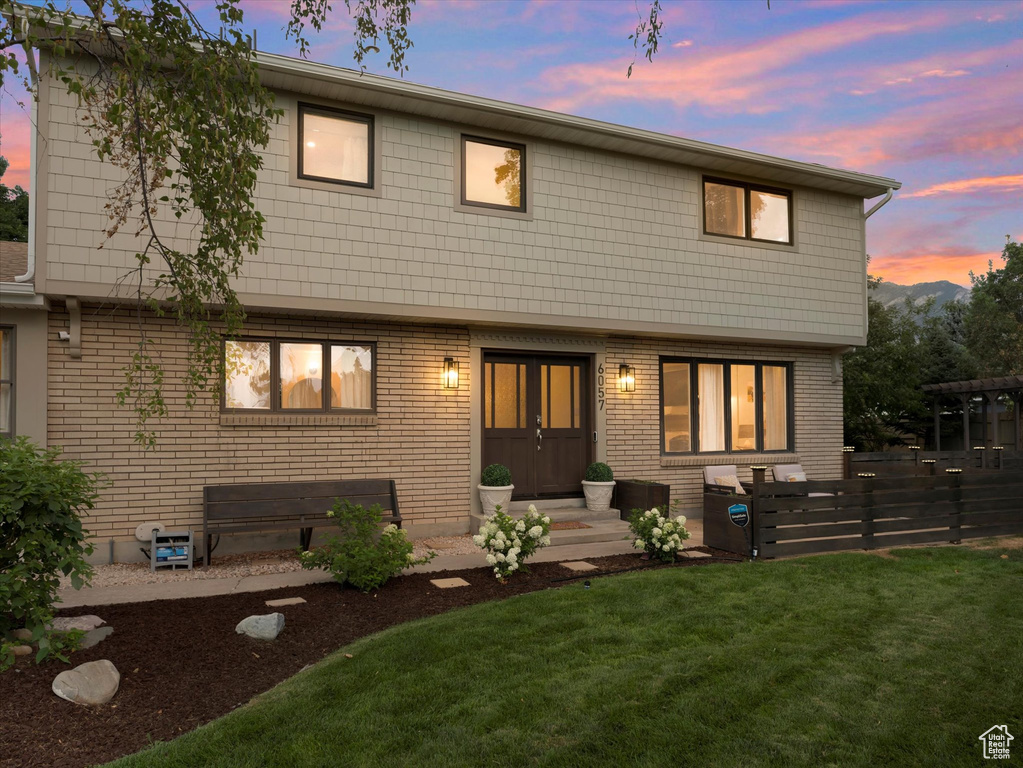 Back house at dusk featuring a yard