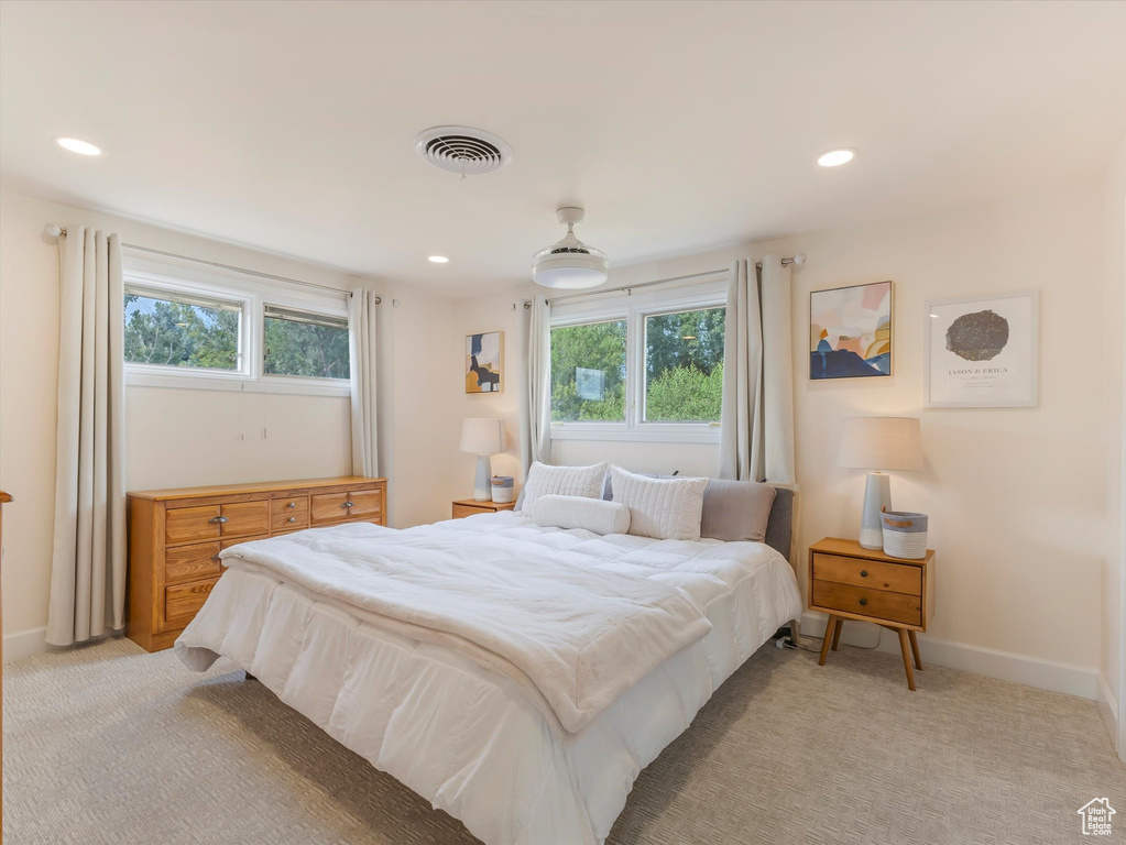 Bedroom featuring light carpet and multiple windows