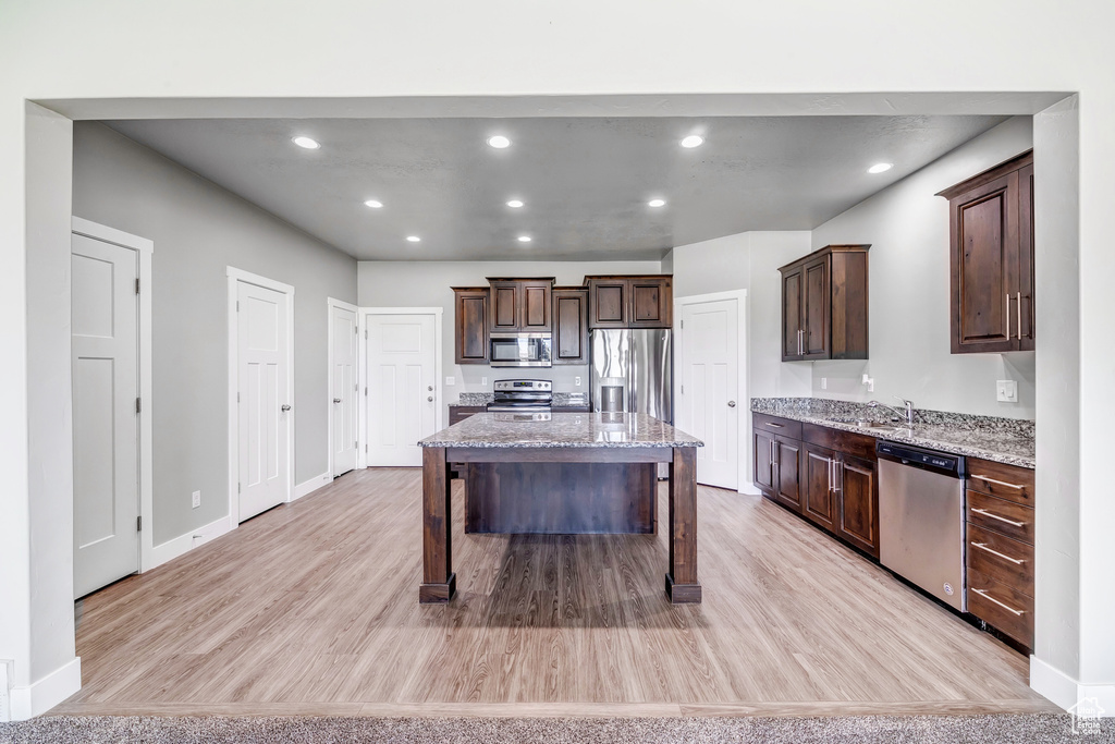 Kitchen featuring appliances with stainless steel finishes, dark brown cabinetry, and light wood-style flooring