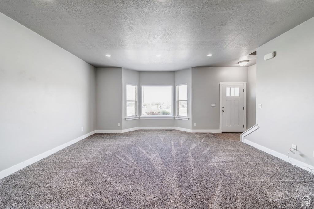 Interior space featuring recessed lighting, carpet flooring, a textured ceiling, and baseboards