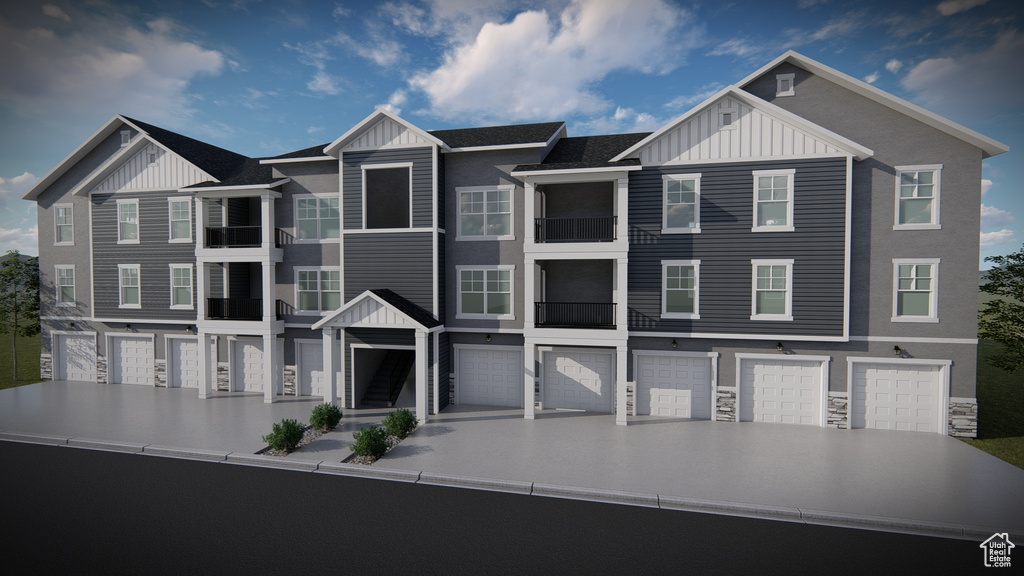 Townhome / multi-family property featuring stone siding, board and batten siding, driveway, and a garage