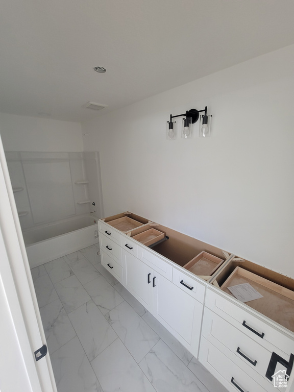 Bathroom featuring marble look tiles and shower / washtub combination