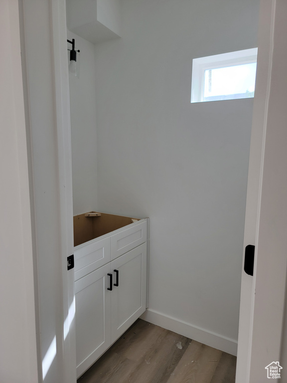 Clothes washing area featuring light wood finished floors and baseboards