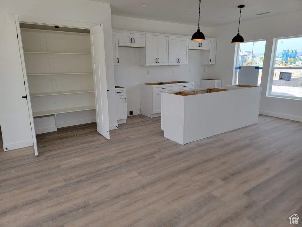 Kitchen with a center island, white cabinets, light wood-style floors, decorative light fixtures, and recessed lighting