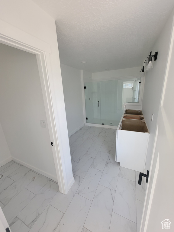 Hallway with light marble finish flooring, baseboards, and a textured ceiling