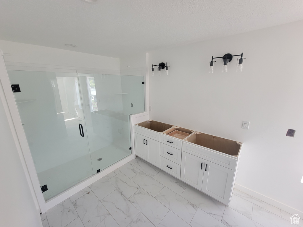 Full bath with marble finish floors, a stall shower, and baseboards