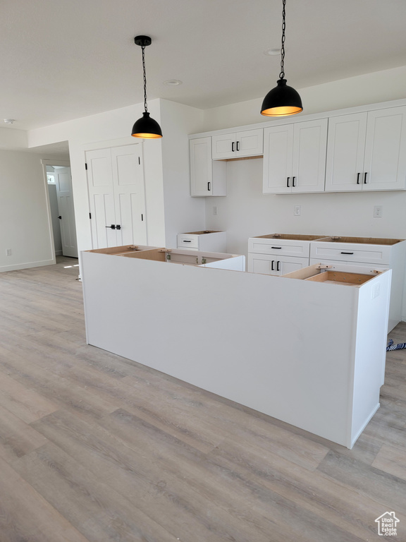 Kitchen featuring light wood-style flooring, white cabinets, hanging light fixtures, and a center island