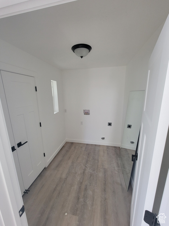Laundry room with electric dryer hookup, light wood finished floors, and baseboards