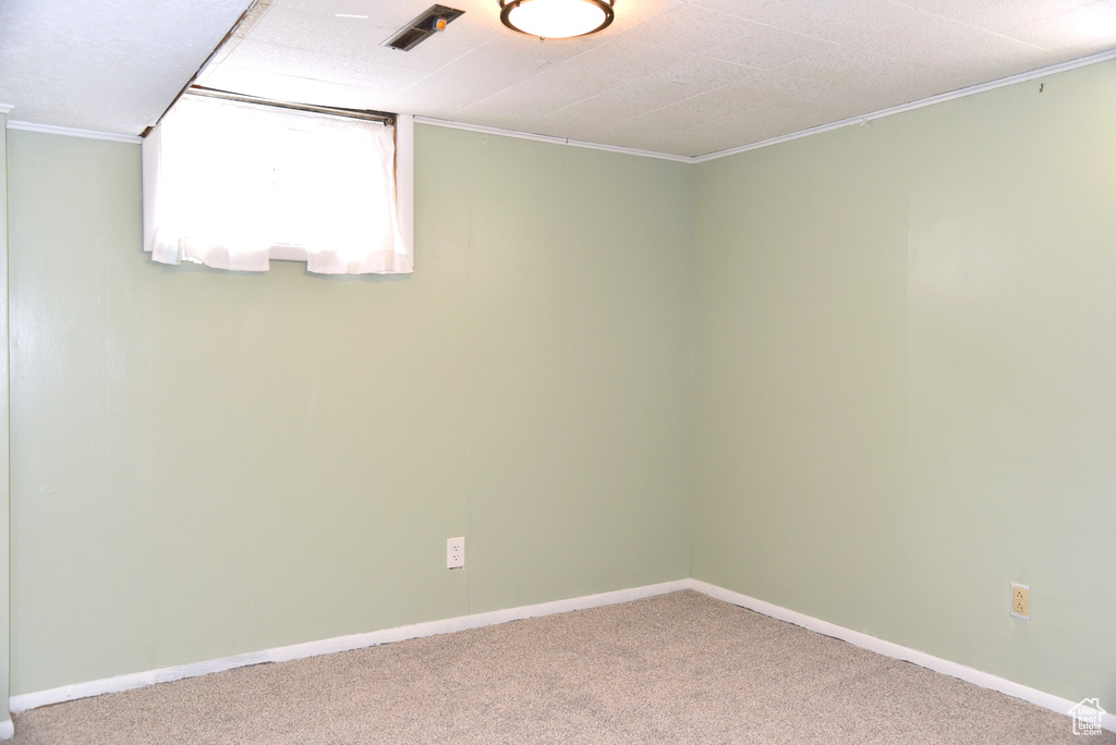 Unfurnished room featuring carpet flooring, baseboards, crown molding, and visible vents