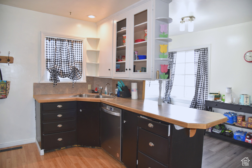 Kitchen with open shelves, dishwasher, light wood-style flooring, a peninsula, and a sink