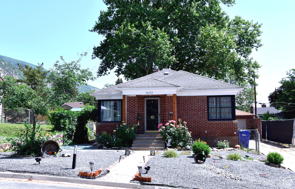 Bungalow-style home featuring brick siding and a shingled roof