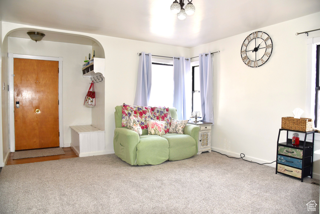 Living area with arched walkways, baseboards, and carpet floors