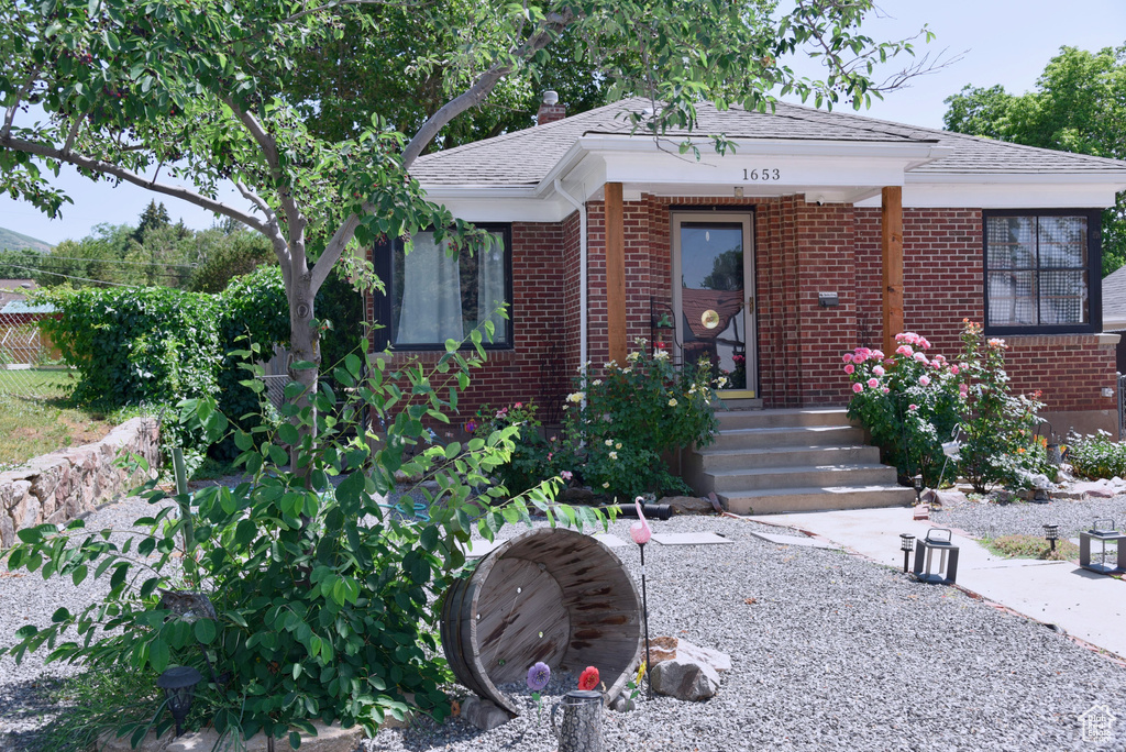 View of front facade featuring brick siding and roof with shingles