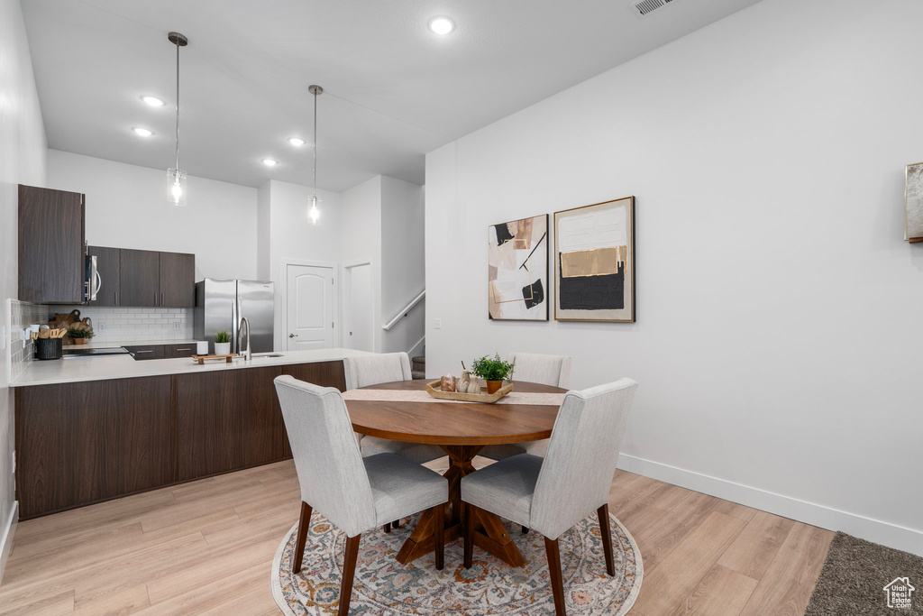 Dining room featuring stairs, recessed lighting, baseboards, and light wood-type flooring