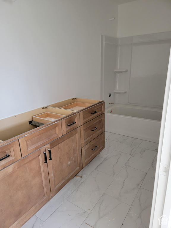 Bathroom with marble finish flooring and shower / washtub combination