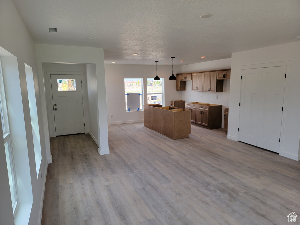 Kitchen featuring light wood-style floors, recessed lighting, baseboards, a center island, and pendant lighting