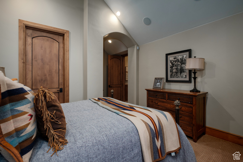 Carpeted bedroom featuring arched walkways and lofted ceiling