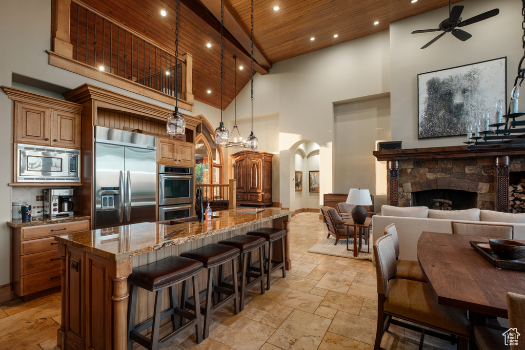Kitchen featuring built in appliances, stone tile floors, arched walkways, high vaulted ceiling, and wood ceiling