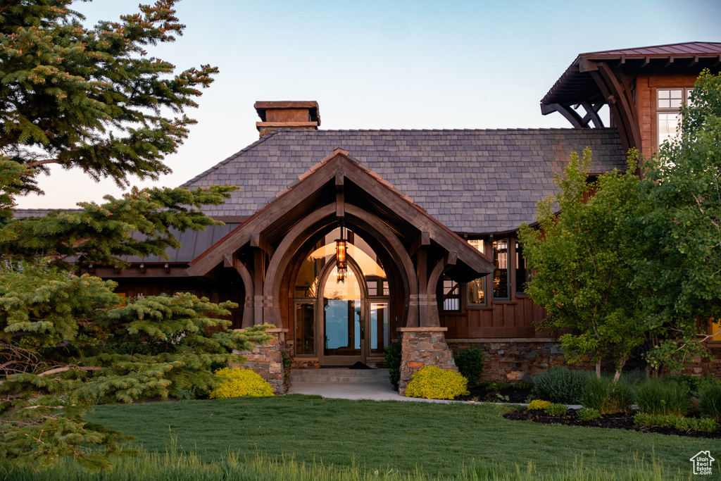 Property entrance with a yard, a chimney, and stone siding