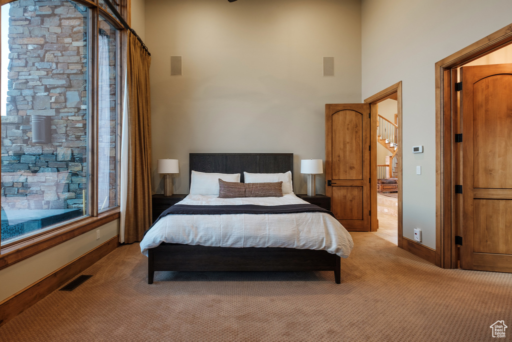 Bedroom featuring light carpet and a towering ceiling