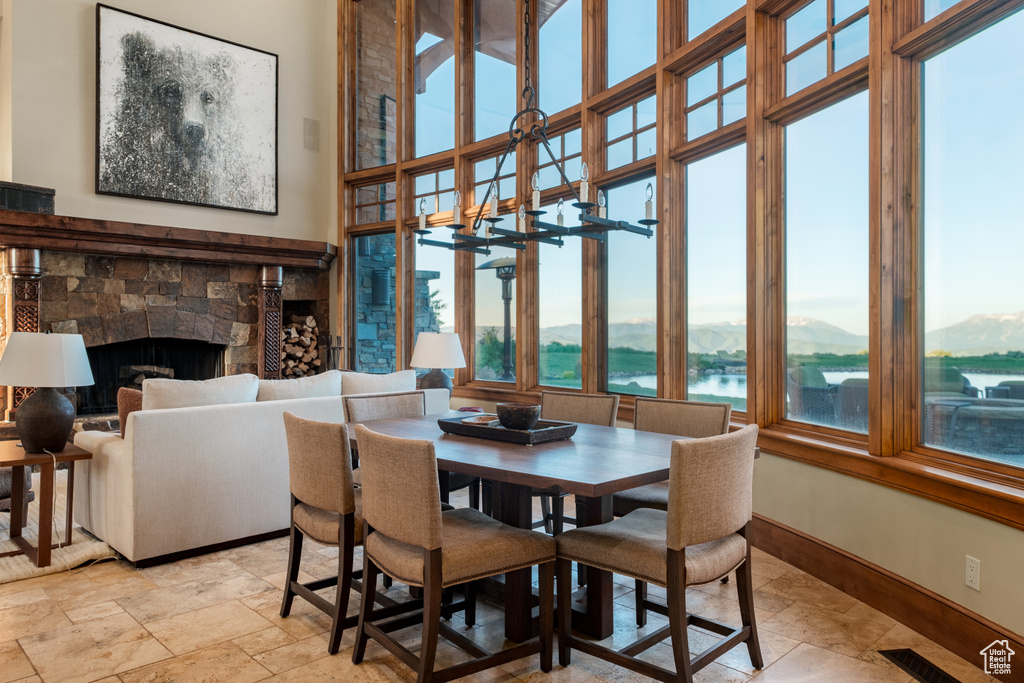 Dining area featuring a fireplace, a water view, and light stone finish flooring