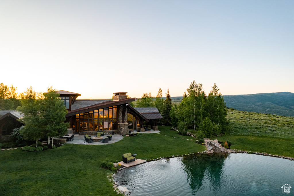 Back of property at dusk with a patio and a yard