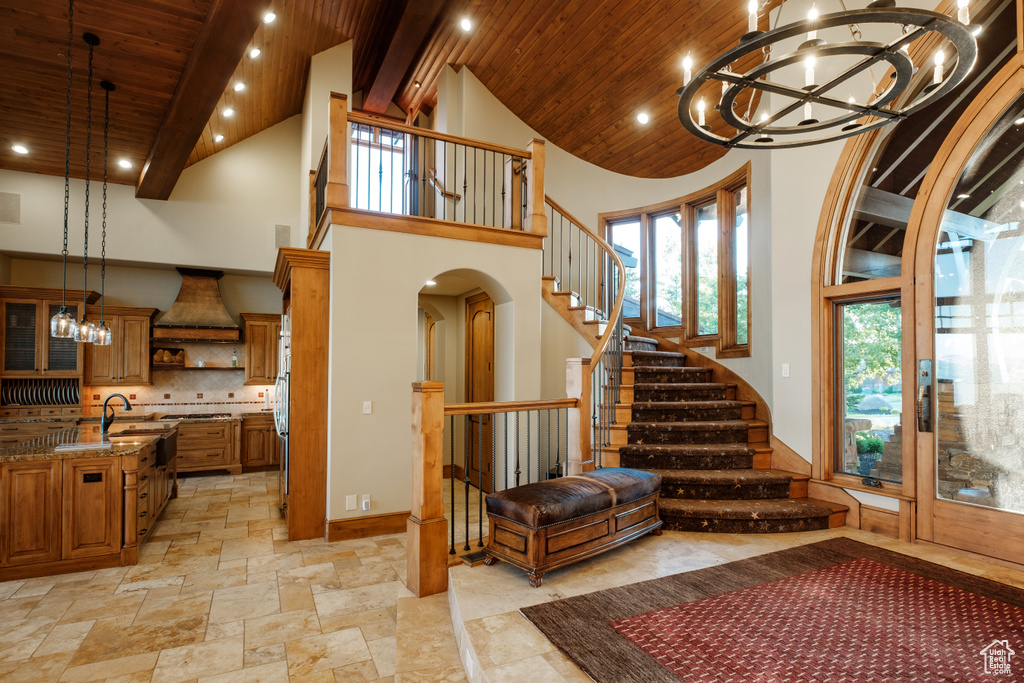 Staircase featuring a chandelier, high vaulted ceiling, recessed lighting, arched walkways, and a wood ceiling with exposed beams