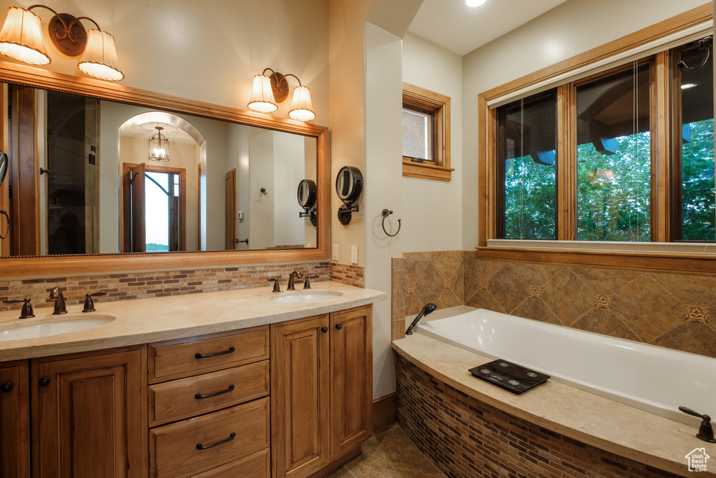 Bathroom with decorative backsplash, a bath, double vanity, and tile patterned flooring