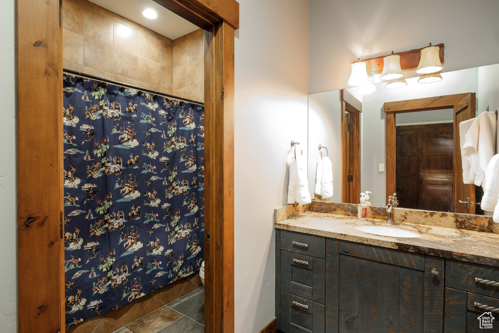 Bathroom featuring vanity, curtained shower, and stone finish floors