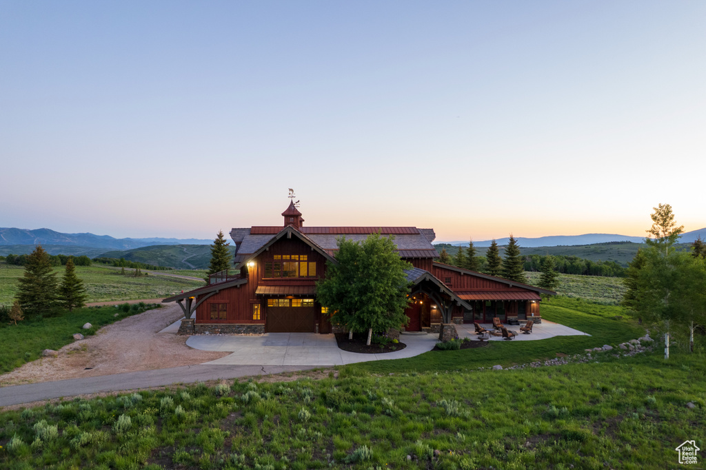 Exterior space featuring driveway, a mountain view, a lawn, board and batten siding, and a garage