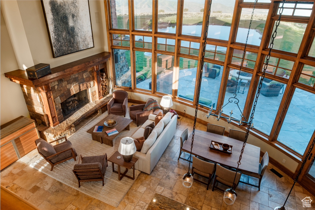 Living room featuring stone tile floors, a water view, a stone fireplace, and plenty of natural light