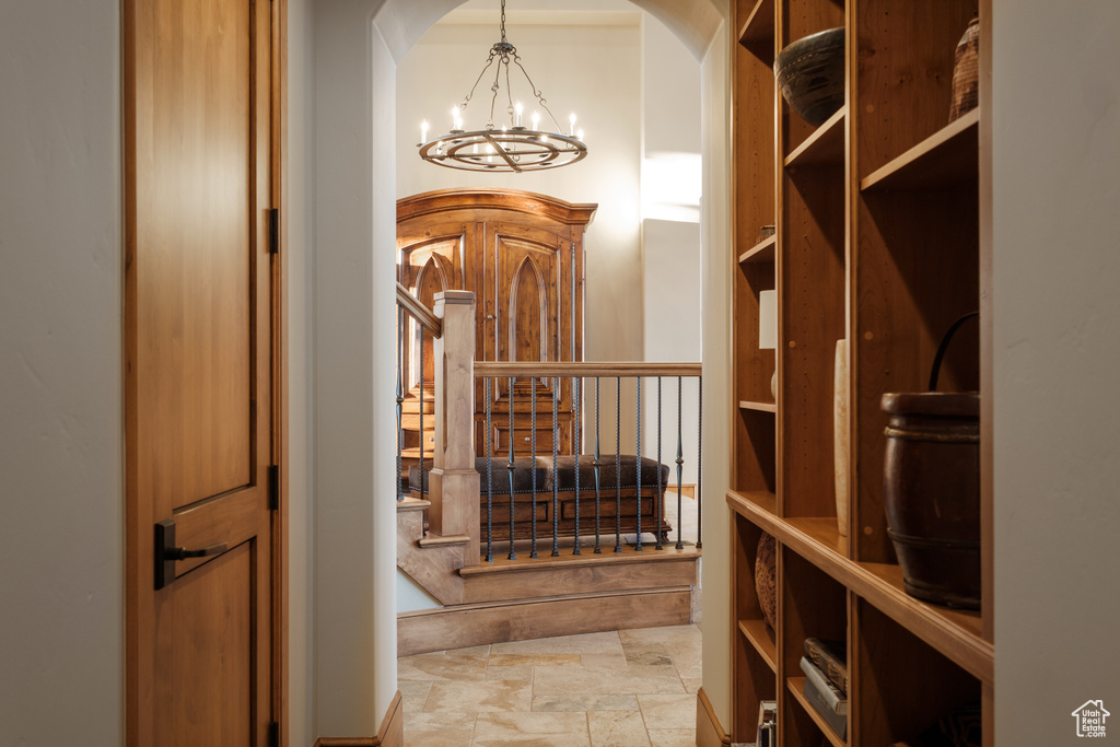Wine area featuring a chandelier, stone tile flooring, and arched walkways