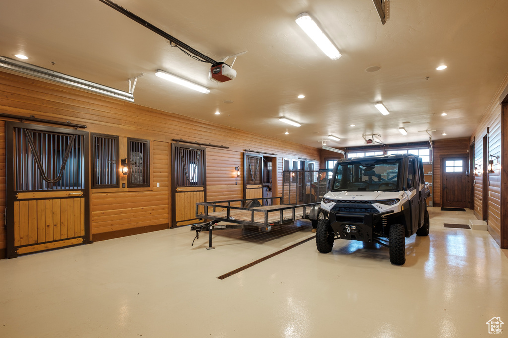 Garage with a garage door opener, recessed lighting, and wood walls