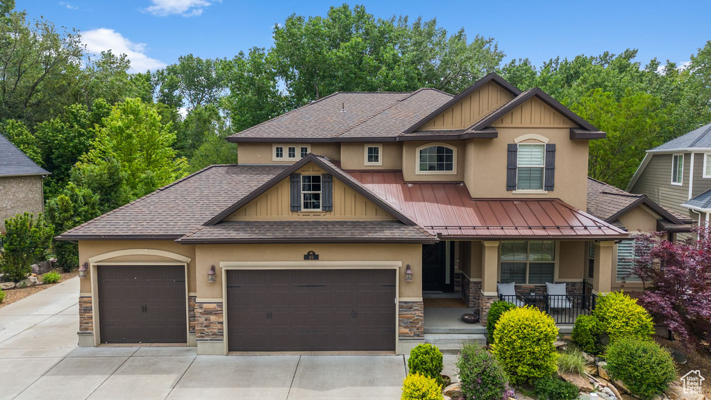 Craftsman-style house with stone siding, a porch, a shingled roof, stucco siding, and an attached garage