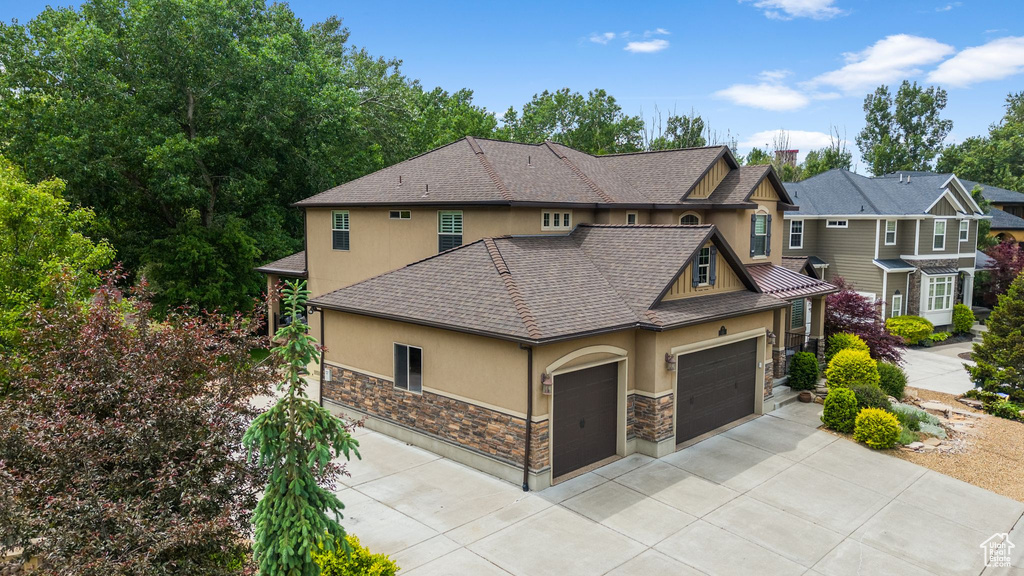 View of home\'s exterior with stucco siding, stone siding, an attached garage, concrete driveway, and roof with shingles