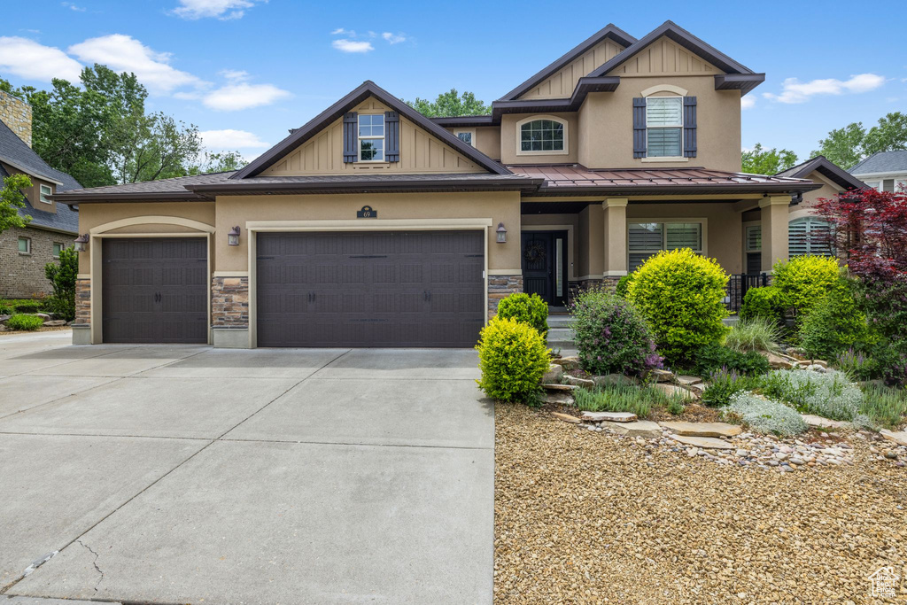 Craftsman-style home with an attached garage, driveway, stone siding, and stucco siding