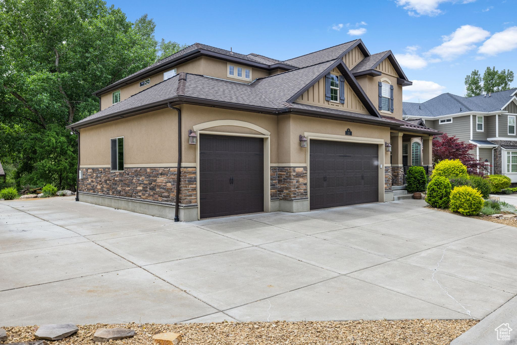Craftsman-style home with stone siding, stucco siding, concrete driveway, a garage, and roof with shingles