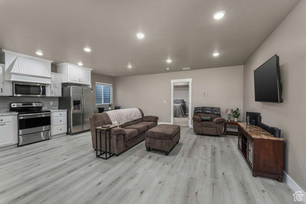 Living area with recessed lighting, baseboards, and light wood-style floors